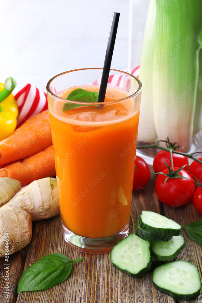 Glass of fresh carrot juice and vegetables on wooden table Glass of fresh carrot juice and vegetables on wooden table