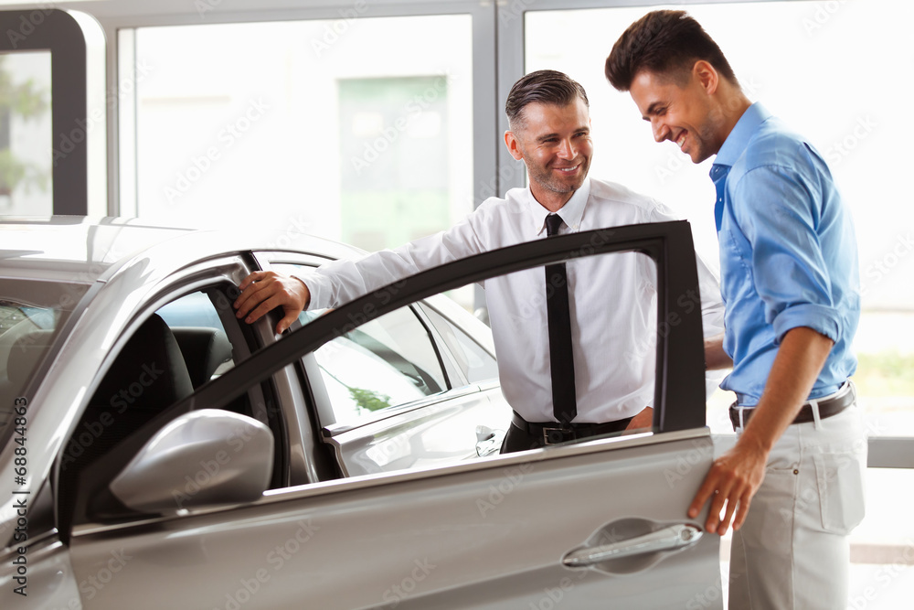 Car Showroom. Vehicle Dealer Showing Young Man New Car