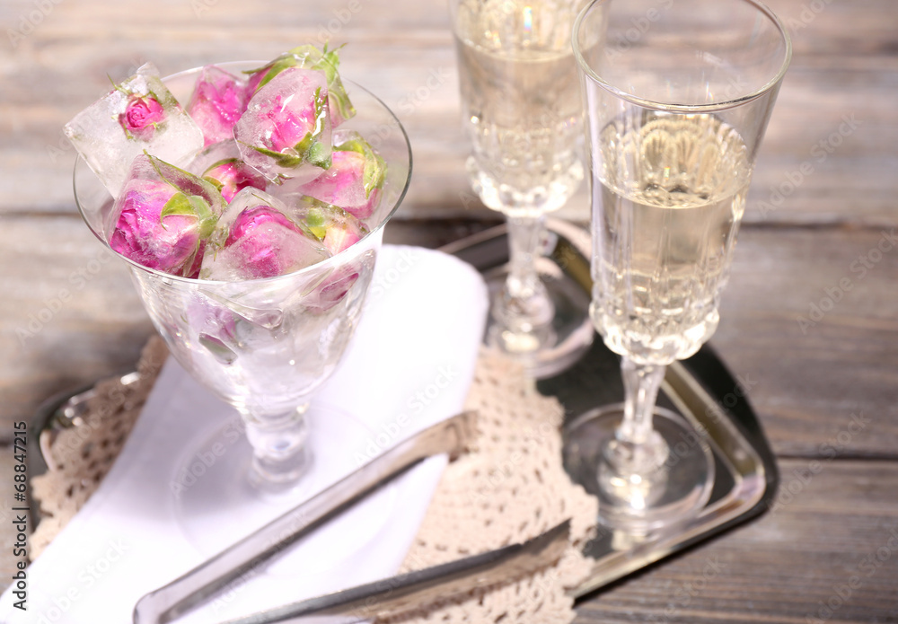 Ice cubes with rose flowers in glass bowl and two glasses with Ice cubes with rose flowers in glass bowl and two glasses with