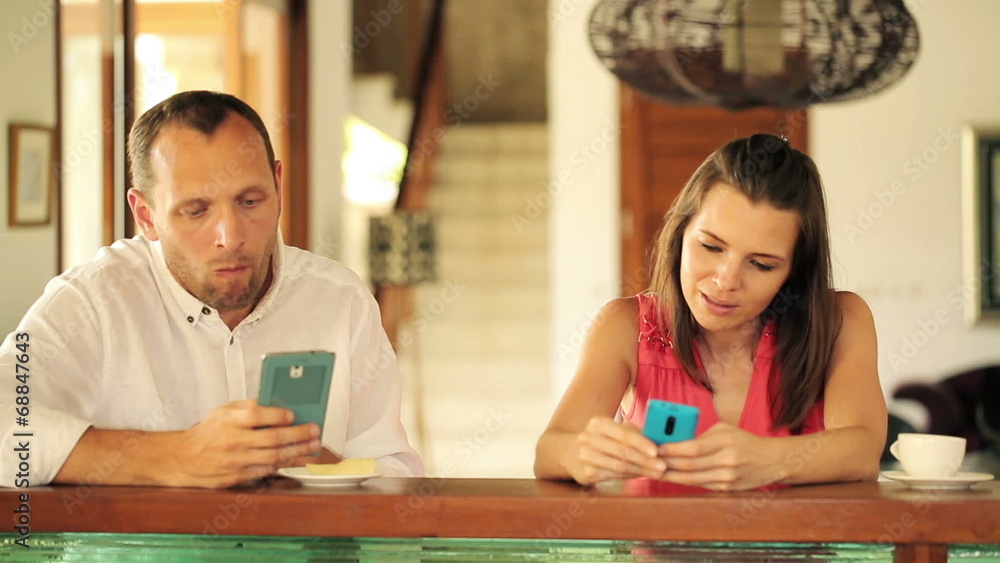 Couple with smartphones by the counter at home Couple with smartphones by the counter at home
