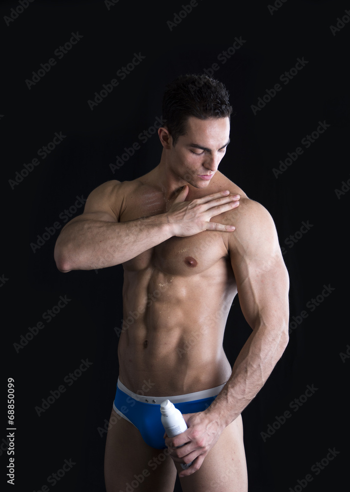 Muscular fit man applying ointment to his shoulder Muscular fit man applying ointment to his shoulder