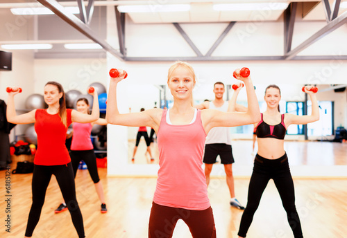 group of smiling people working out with dumbbells