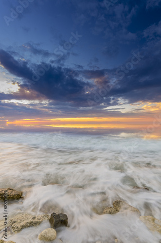 a fiery sunset and the waves lapping on the rocky shore