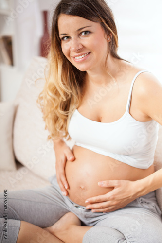 Pregnant woman sitting in her living room and relaxing Free Download Pregnant woman sitting in her living room and relaxing - GFXLoad