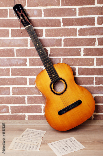 Guitar on the floor on brick wall background © Africa Studio