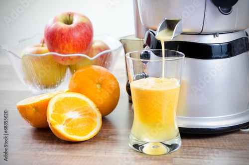Juicer and orange juice. Fruits in background photo