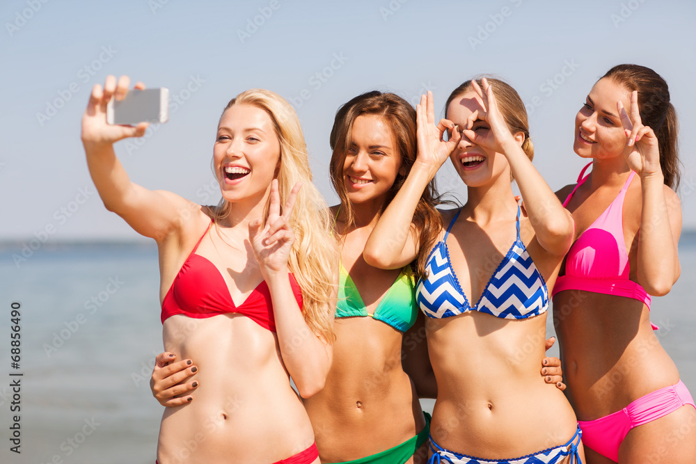 group of smiling women making selfie on beach