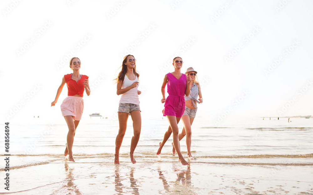 group of smiling women running on beach