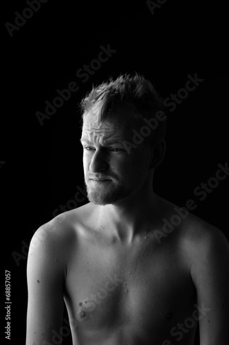 Portrait of young man frowning his forehead on black background