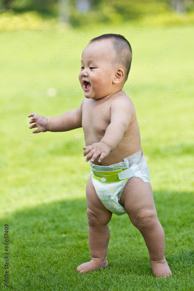 Oriental baby learning to walk in the park lawn Oriental baby learning to walk in the park lawn