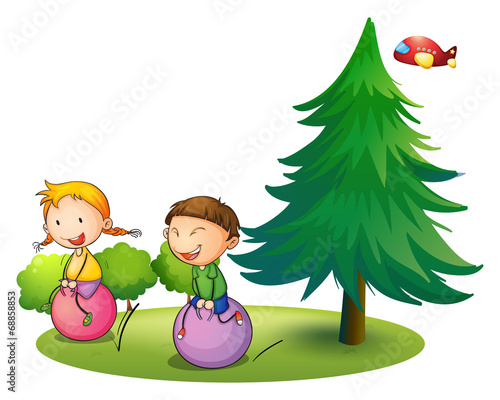 Kids playing with the bouncing balloons near the pine tree