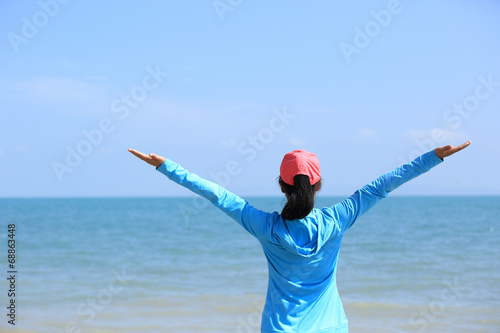 young woman open arms to blue sky and sea