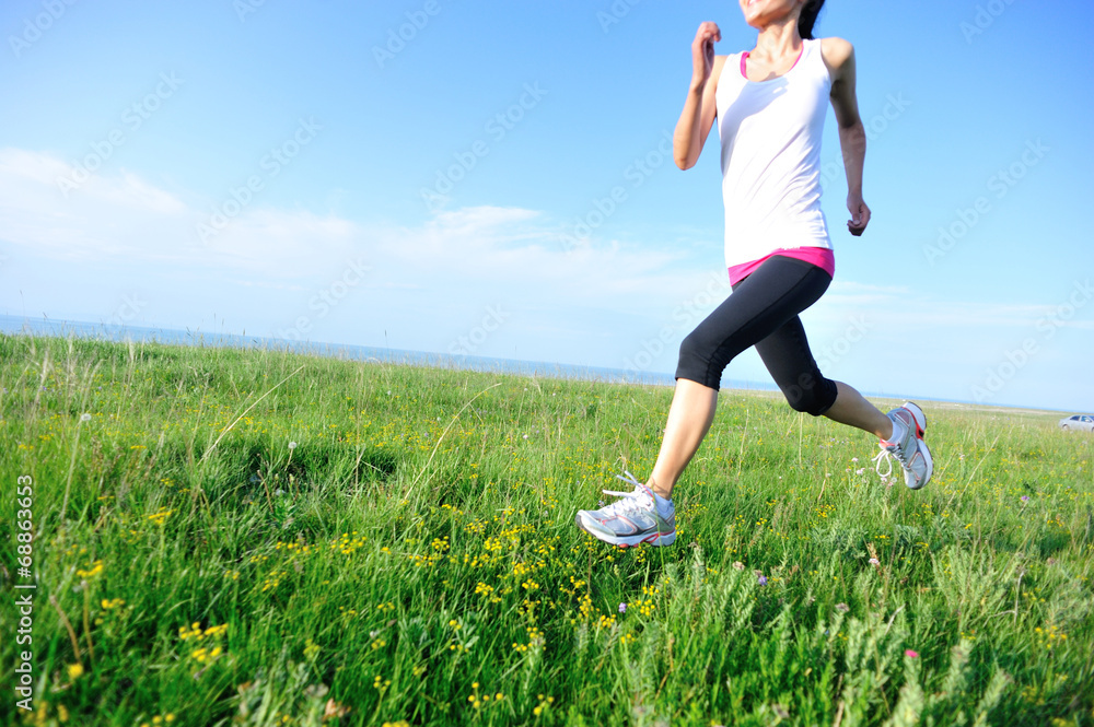 Runner athlete legs running on grass seaside Runner athlete legs running on grass seaside