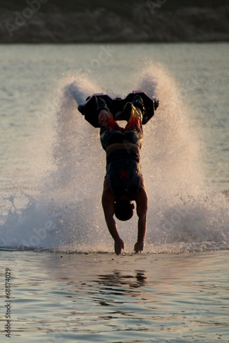 Flyboarder in silhouette diving forwards towards camera photo