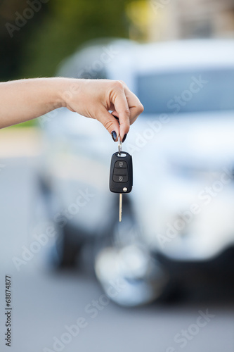 Car defocused on background and woman hand with key © Kekyalyaynen