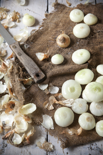 small golden onions with peel and some peeled on rustic set