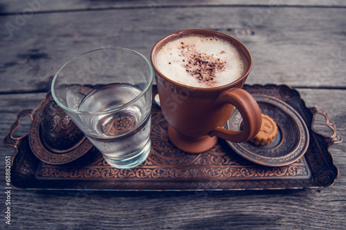 Чашка кофе, стакан воды и печенье на деревянном столе.