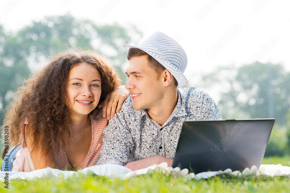couple lying together in a park with laptop couple lying together in a park with laptop