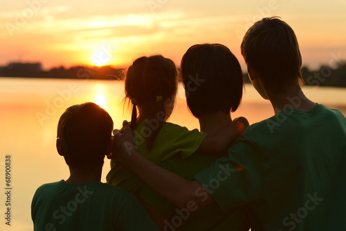 Family near the river against the sunset
