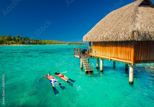 Young couple snorkling from hut over tropical lagoon
