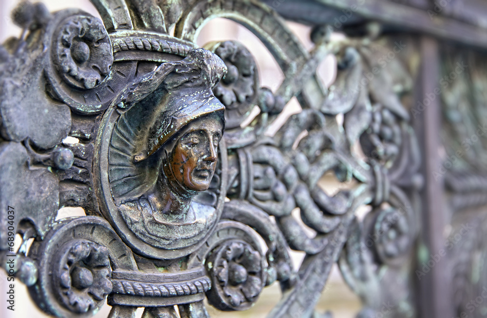 Vintage bronze fence with human head at Piazza Duomo in Bergamo