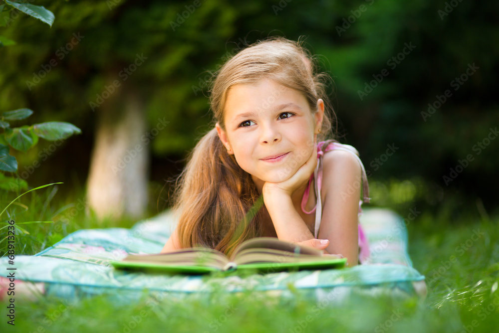 Little girl is reading a book outdoors Little girl is reading a book outdoors
