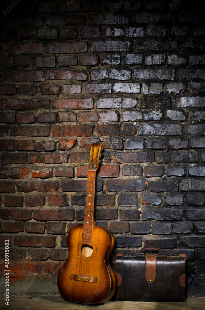 guitar and retro bag on brick wall background