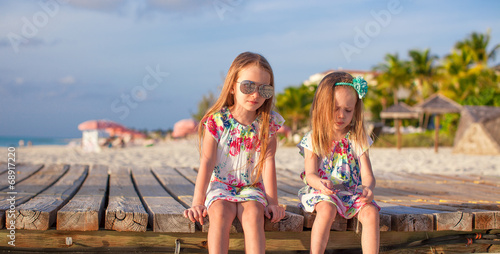 Two happy little girls enjoy vacation on white beach