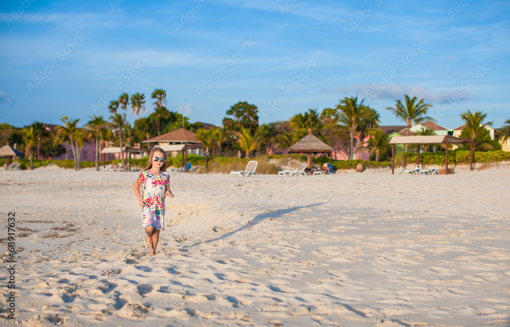 Adorable little girl walking at white tropical beach on sunset