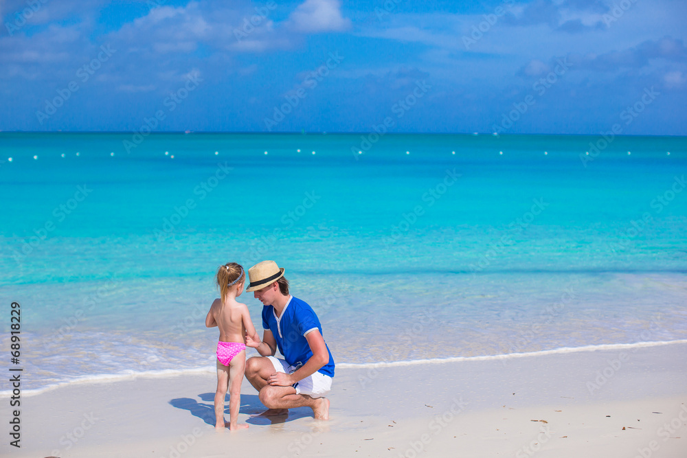 Adorable little girl and father at beach during summer vacation