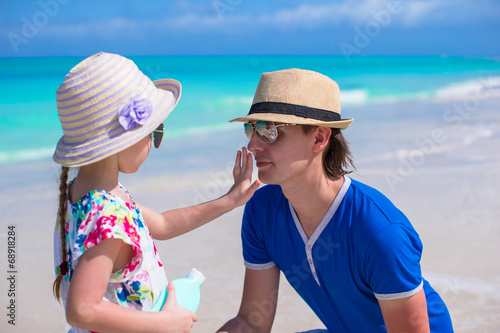 Little girl apply sunscreen on nose of her dad © travnikovstudio