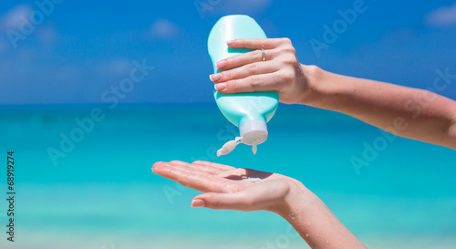 Fotografie Woman hands putting sunscreen from suncream bottle