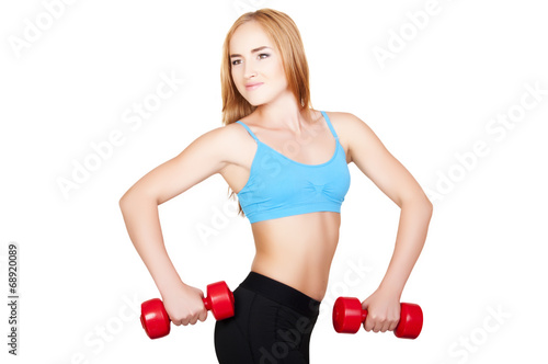 Young fit woman lifting dumbbells on white background