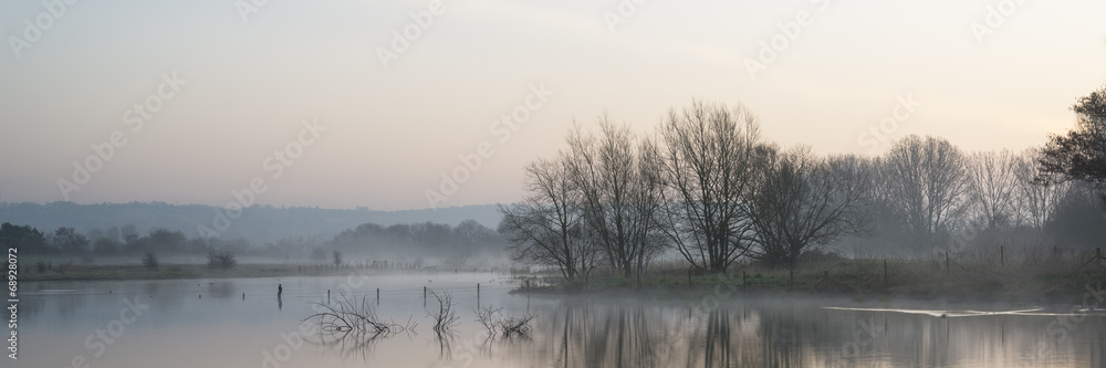 Panorama landscape of lake in mist with sun glow at sunrise Panorama landscape of lake in mist with sun glow at sunrise