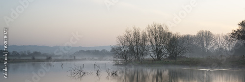 Panorama landscape of lake in mist with sun glow at sunrise #68928072