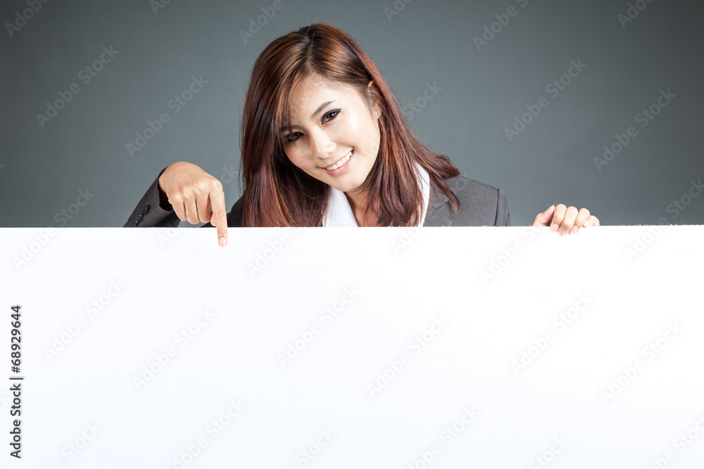 Asian businesswoman stand behind a blank billboard , point down Asian businesswoman stand behind a blank billboard , point down