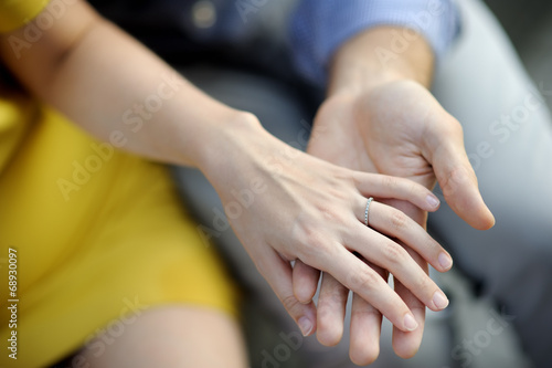 Man holding woman's hand with engagement ring