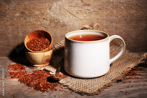 Cup of tasty rooibos tea, on wooden table photo