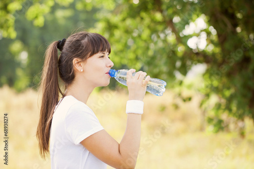 Runner woman drinking water after jogging