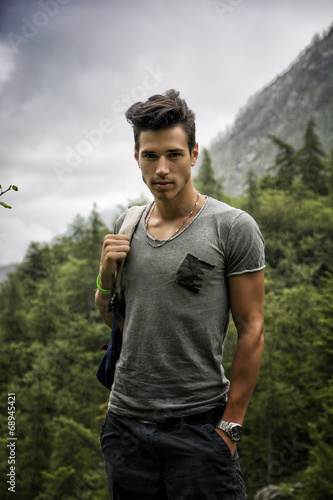 Handsome athletic young man with backpack in mountains