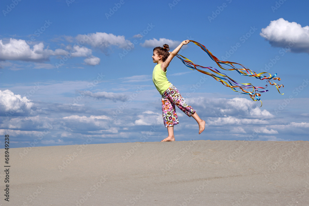 happy little girl with colorful ribbons on beach