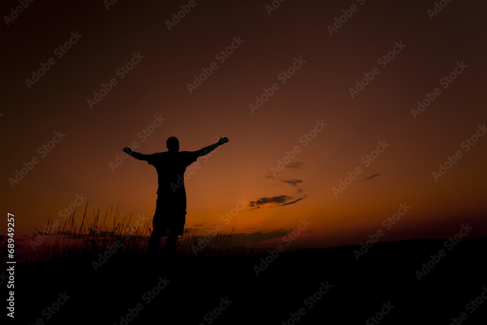 Man worshiping with his hands up in the sunset sky