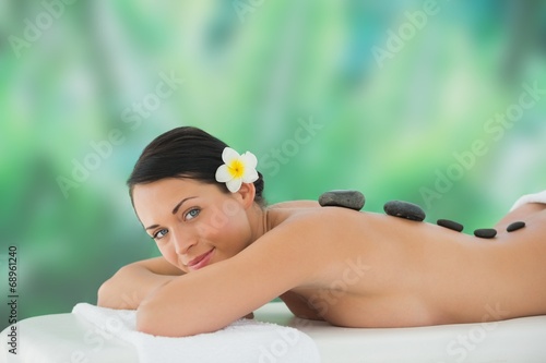 Beautiful brunette enjoying hot stone massage smiling at camera