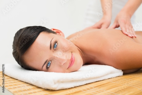 Beautiful brunette enjoying a back massage smiling at camera