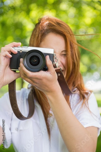 Pretty redhead taking a photo in the park © WavebreakmediaMicro