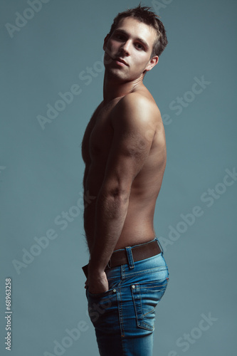 Handsome muscular male model with nice abs in blue jeans