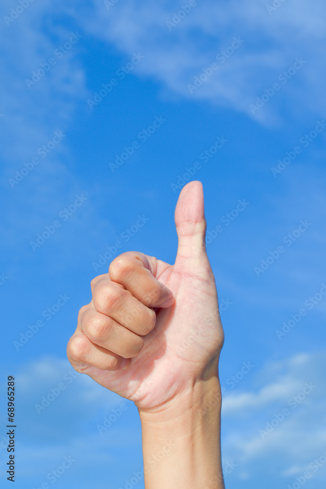 Closeup hand thumbs up sign blue sky background Closeup hand thumbs up sign blue sky background