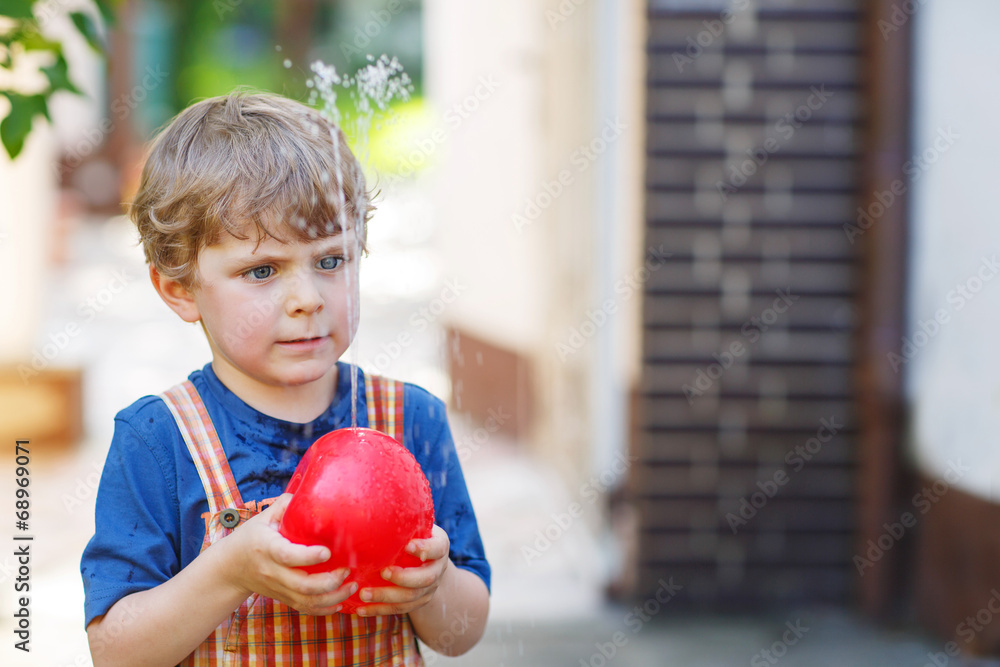 Fototapeta premium Little toddler boy having fun with splashing water in summer gar