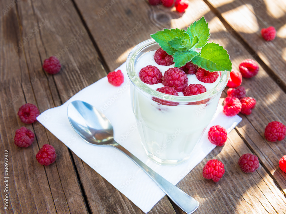 Glass of yogurt with raspberry on wooden table Glass of yogurt with raspberry on wooden table