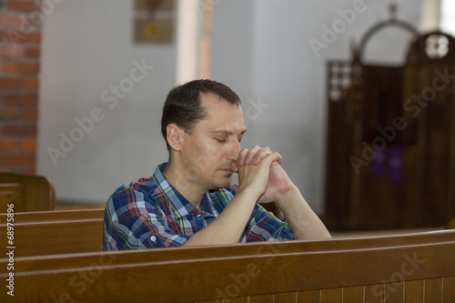 Handsome young man praying in a church